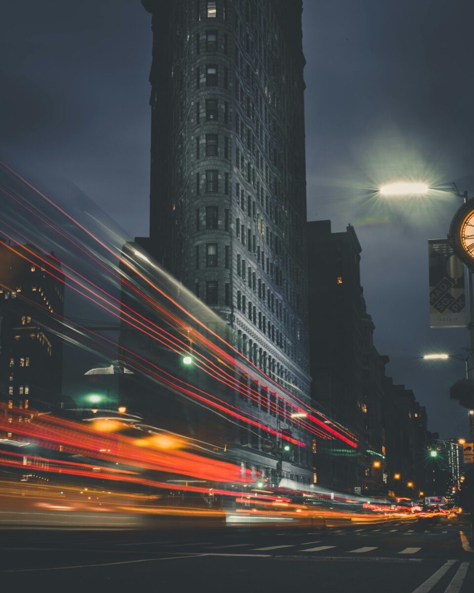 Night view of the Flatiron Building with vibrant light trails in New York City.